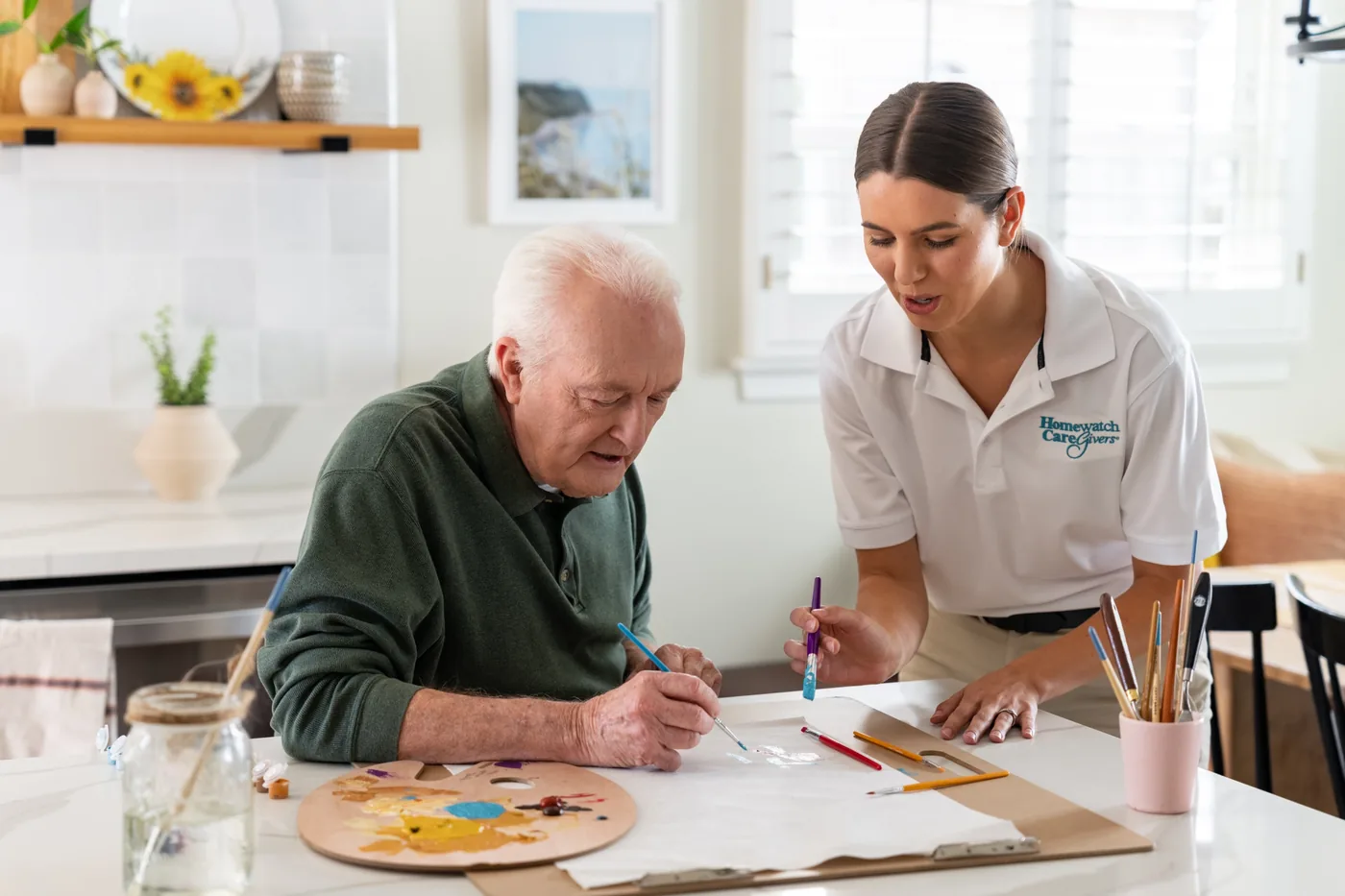 A Homewatch caregiver with a client at his kitchen table